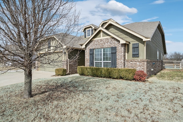 craftsman-style house with a garage, driveway, brick siding, and fence