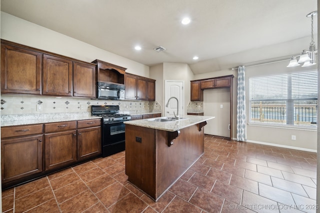 kitchen with tasteful backsplash, a center island with sink, a breakfast bar area, black appliances, and a sink