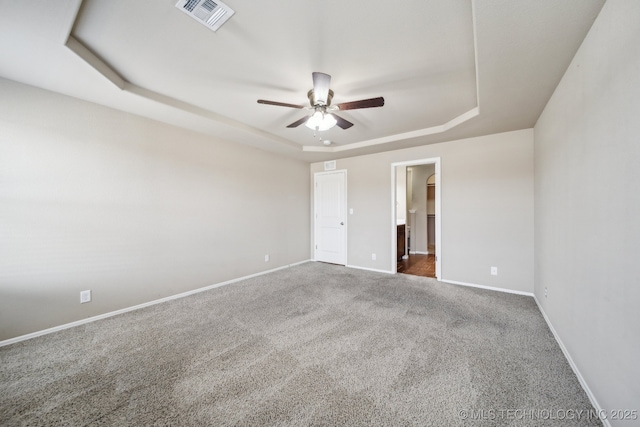 unfurnished bedroom with ceiling fan, carpet flooring, visible vents, baseboards, and a tray ceiling