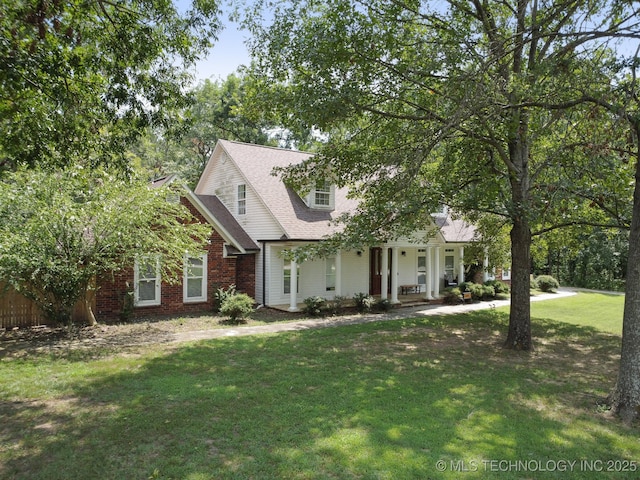 new england style home with covered porch, a front lawn, and brick siding