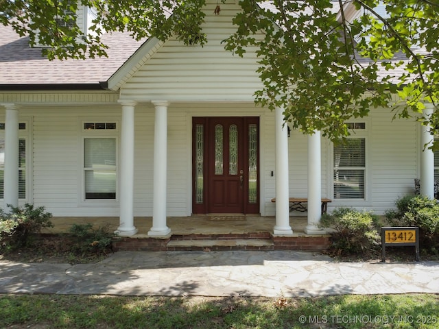 property entrance featuring a porch and roof with shingles