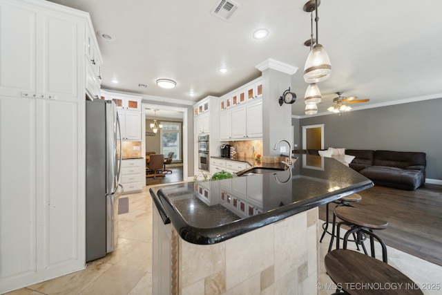 kitchen featuring stainless steel appliances, visible vents, a sink, and ornamental molding