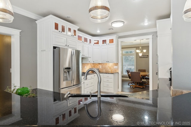 kitchen featuring white cabinets, ornamental molding, tasteful backsplash, stainless steel fridge, and glass insert cabinets