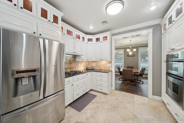 kitchen featuring visible vents, white cabinets, stainless steel appliances, crown molding, and backsplash