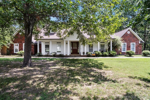 view of property hidden behind natural elements with a front lawn and brick siding