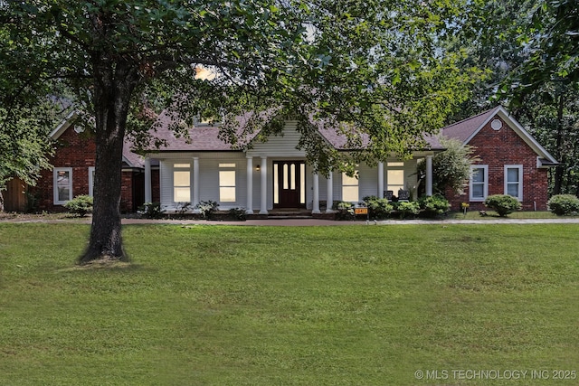 view of front of house with a front lawn, roof with shingles, and brick siding