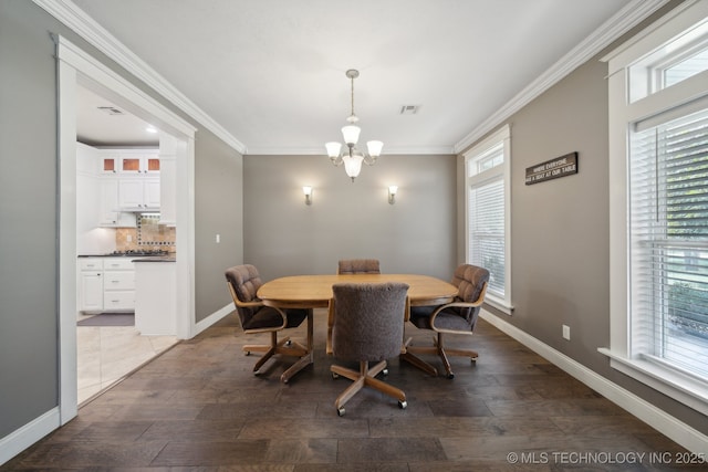 dining area with wood finished floors, crown molding, baseboards, and an inviting chandelier