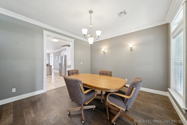 dining room with dark wood-type flooring, visible vents, ornamental molding, and an inviting chandelier