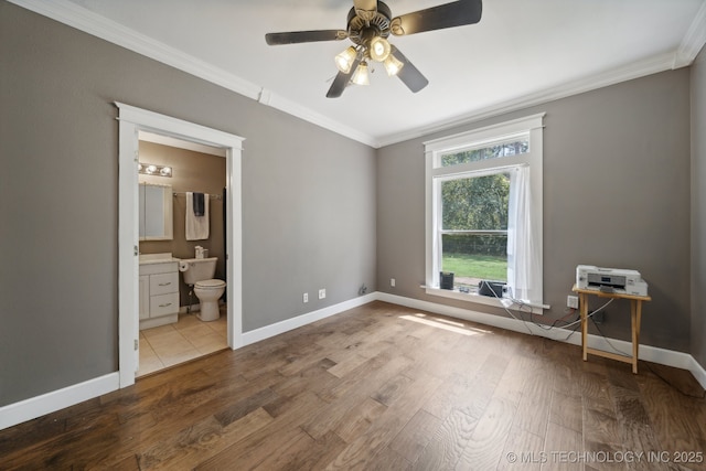 unfurnished bedroom with baseboards, ensuite bath, ceiling fan, wood finished floors, and crown molding