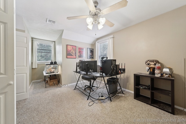 carpeted office space featuring a ceiling fan, visible vents, vaulted ceiling, and baseboards