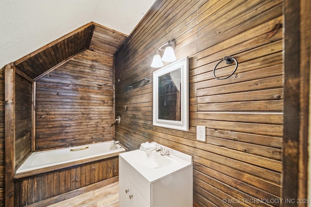 full bath featuring tub / shower combination, wood walls, and vanity