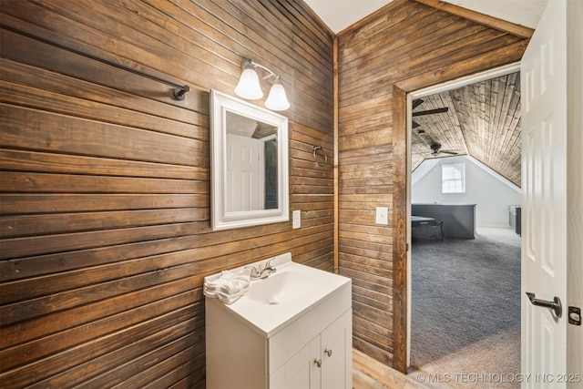 bathroom with lofted ceiling, vanity, and wooden walls