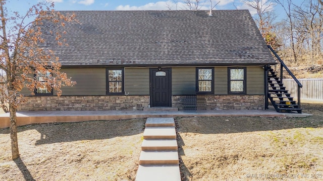 view of front of home featuring stone siding, a shingled roof, and stairway