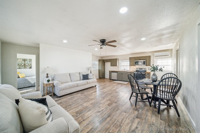 living room with baseboards, a wall mounted air conditioner, wood finished floors, and recessed lighting