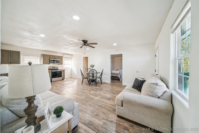 living area with light wood-style flooring, baseboards, a ceiling fan, and recessed lighting