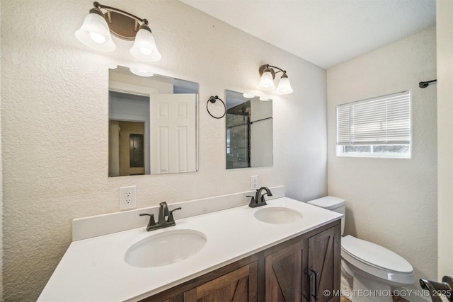 full bath featuring a textured wall, double vanity, a sink, and toilet