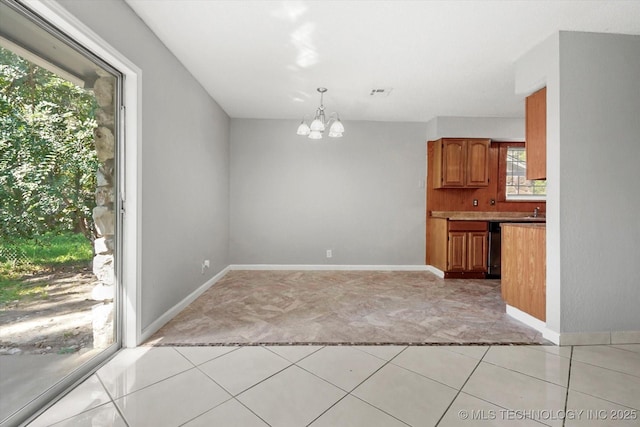 interior space featuring a chandelier, visible vents, baseboards, light countertops, and brown cabinetry