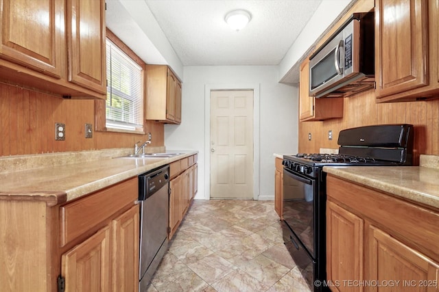 kitchen featuring a textured ceiling, stainless steel appliances, a sink, and light countertops