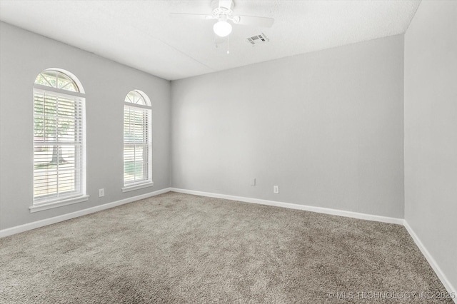 empty room with carpet floors, baseboards, visible vents, and ceiling fan