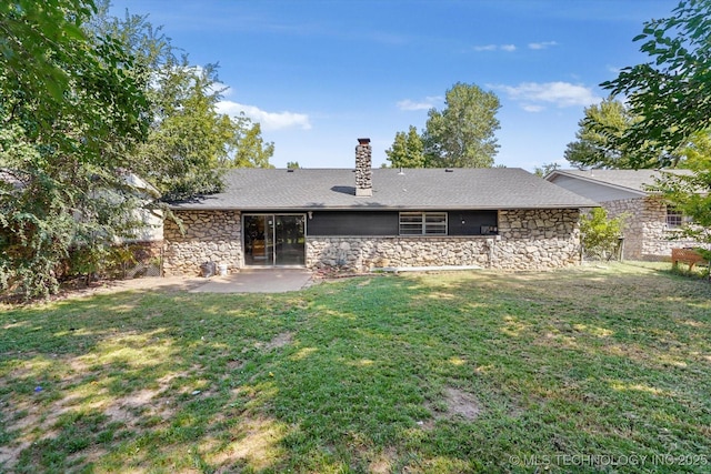 rear view of property featuring a patio area, a chimney, stone siding, and a lawn