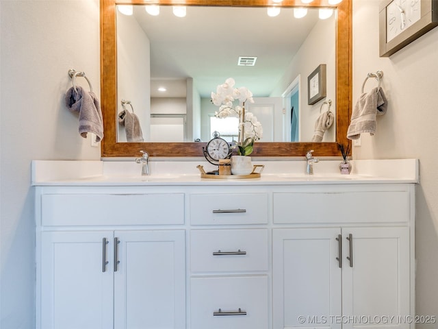 bathroom with double vanity, visible vents, and a sink