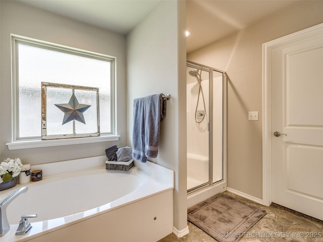 bathroom with a shower stall, baseboards, and a bath