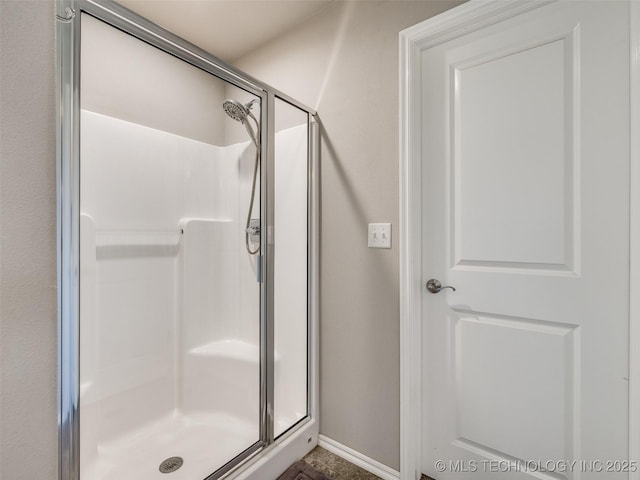 full bath featuring a shower stall and baseboards