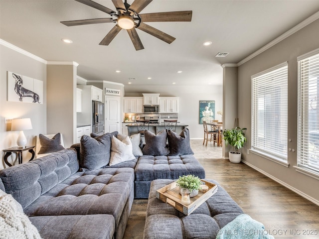 living area with ornamental molding, dark wood-type flooring, visible vents, and baseboards