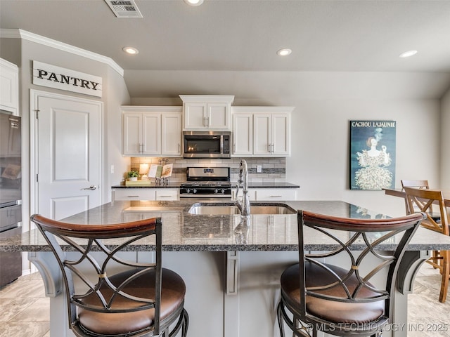 kitchen featuring tasteful backsplash, visible vents, stainless steel appliances, and a sink