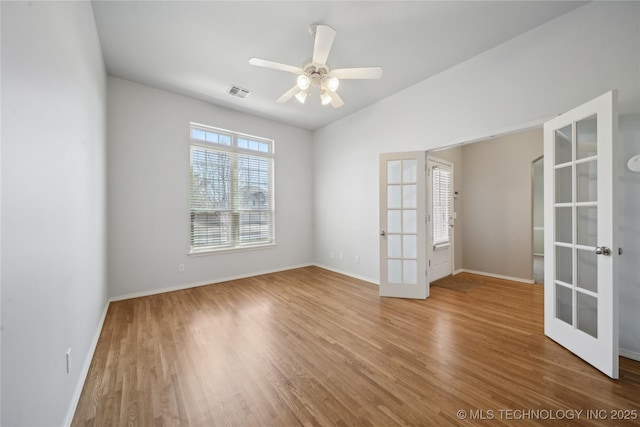 empty room with french doors, visible vents, ceiling fan, wood finished floors, and baseboards