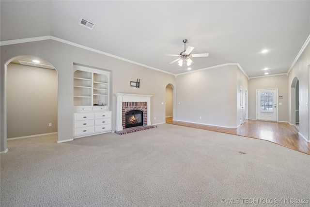 unfurnished living room featuring baseboards, visible vents, arched walkways, built in features, and ceiling fan