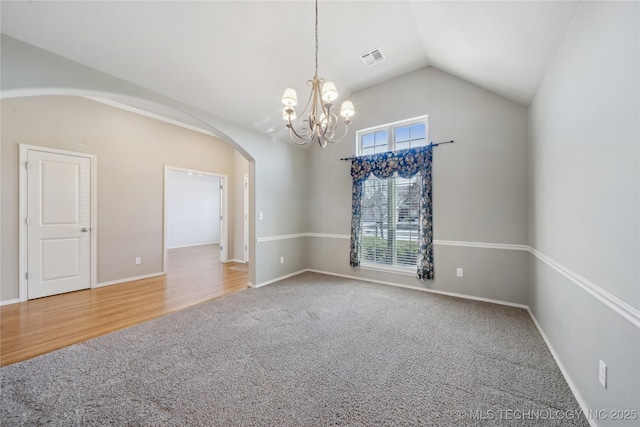 empty room with arched walkways, carpet flooring, visible vents, baseboards, and vaulted ceiling