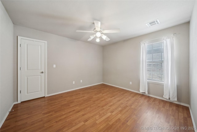 empty room featuring light wood-style floors, visible vents, ceiling fan, and baseboards