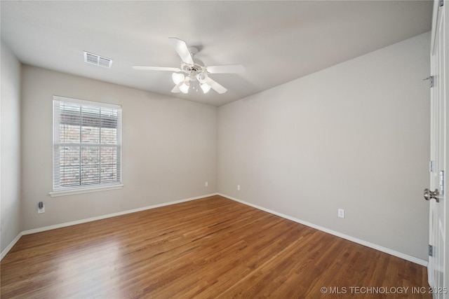 spare room with a ceiling fan, visible vents, baseboards, and wood finished floors