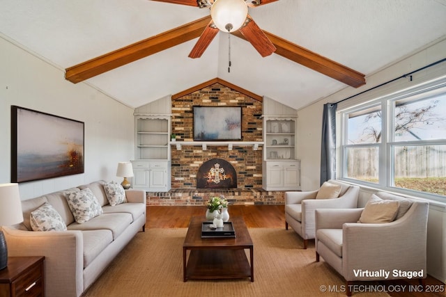 living area featuring lofted ceiling with beams, a fireplace, wood finished floors, and built in features