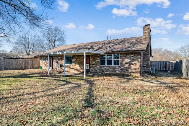 view of front of property with a fenced backyard, a front yard, a chimney, and brick siding