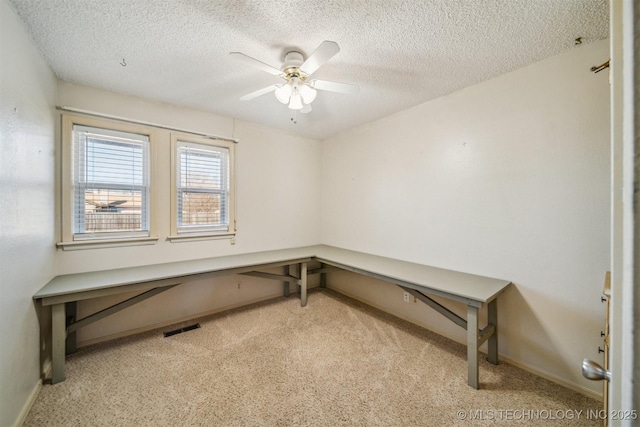 office area with baseboards, visible vents, a ceiling fan, light colored carpet, and a textured ceiling