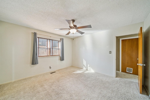 empty room with a ceiling fan, carpet, visible vents, and a textured ceiling