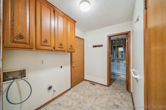 laundry room with a textured ceiling, gas dryer hookup, hookup for an electric dryer, washer hookup, and cabinet space