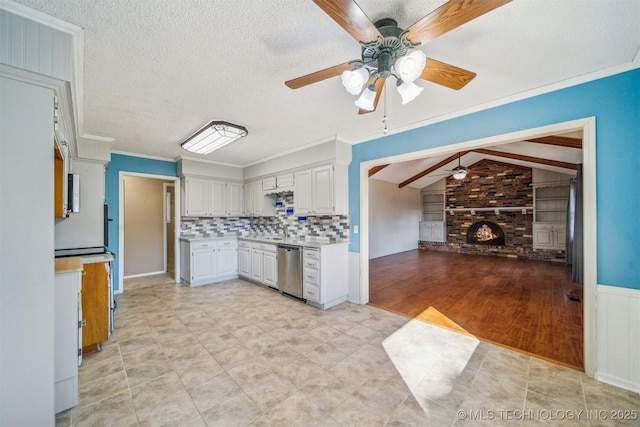 kitchen featuring dishwasher, lofted ceiling with beams, light countertops, a textured ceiling, and a fireplace