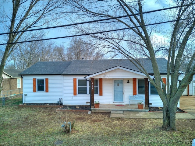 view of front facade with a front lawn, roof with shingles, and fence