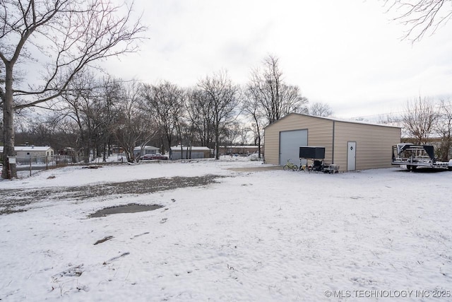 yard layered in snow with a detached garage, fence, and an outdoor structure