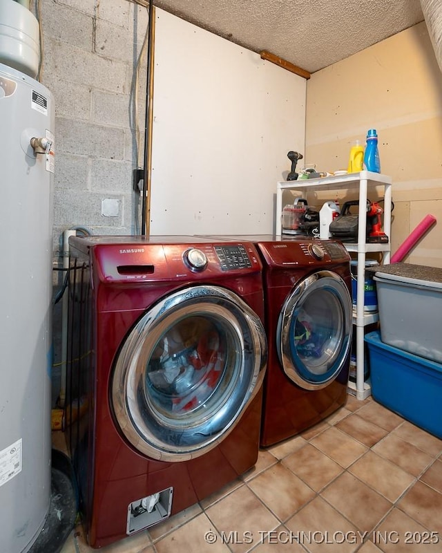 washroom featuring concrete block wall, laundry area, a textured ceiling, washing machine and dryer, and water heater