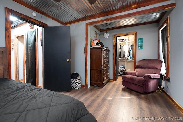 bedroom with ornamental molding, wood finished floors, wood ceiling, and baseboards