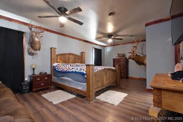 bedroom with crown molding, visible vents, ceiling fan, and wood finished floors