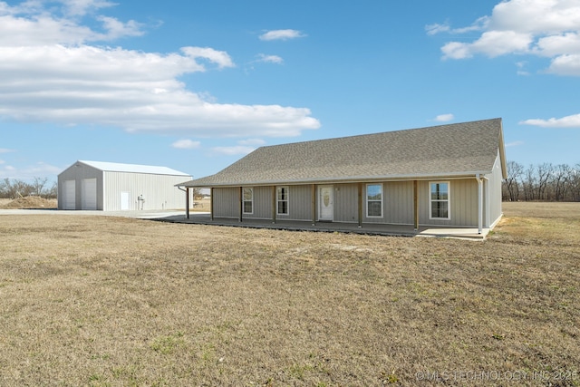 view of front of home with a garage, an outdoor structure, a shingled roof, and a front lawn