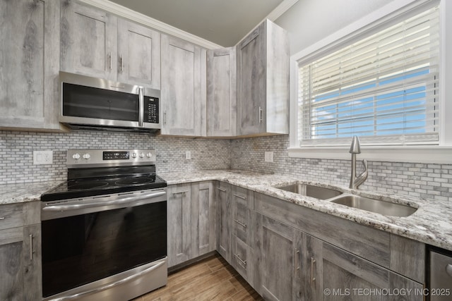 2374 N 205th Rd, Beggs, OK 74421 - kitchen with stainless steel appliances, a sink, decorative backsplash, light wood-style flooring, and light stone counters