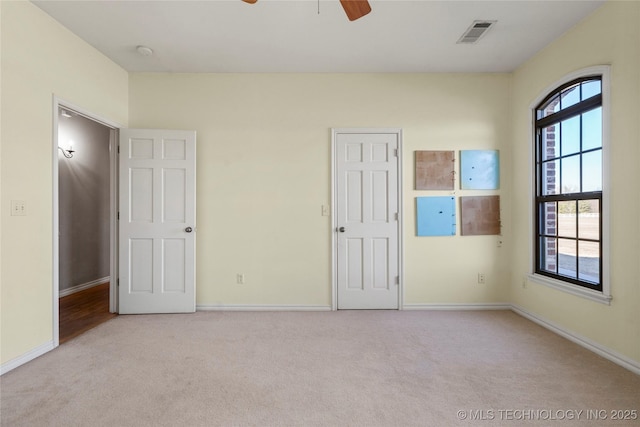 unfurnished bedroom with a ceiling fan, carpet, visible vents, and baseboards