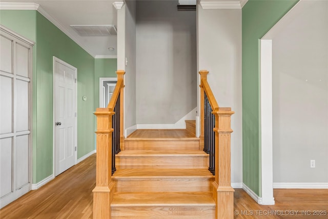 stairs featuring baseboards, crown molding, visible vents, and wood finished floors