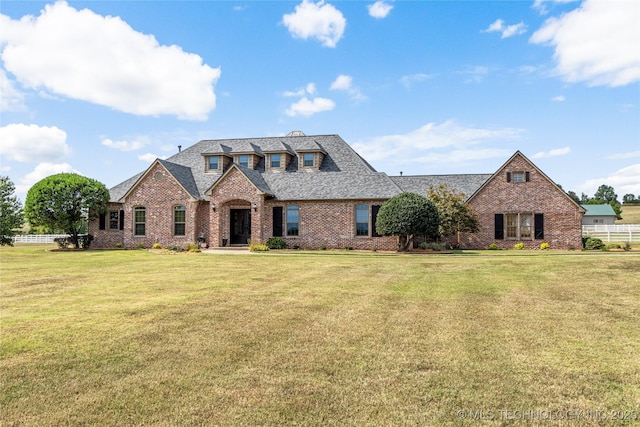 view of front of house featuring brick siding, roof with shingles, and a front yard